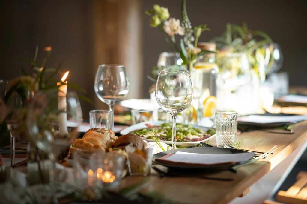 Gedeckter Holztisch mit Gläsern, Kerzen und Blumen