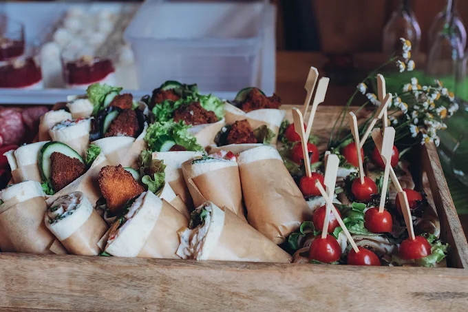 Wraps and tomato skewers in a wooden box