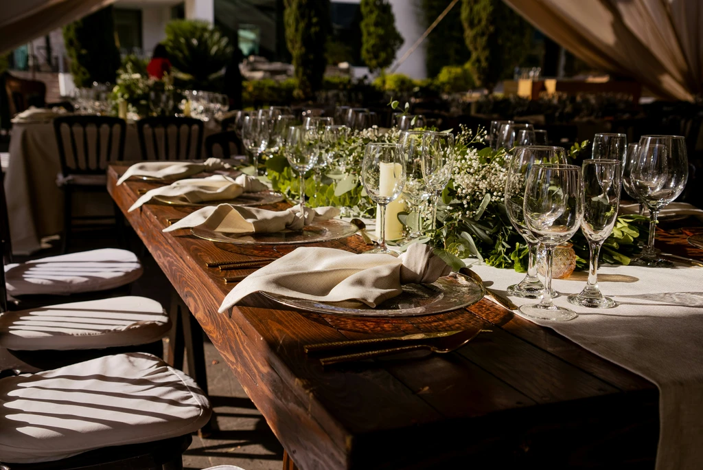Festlich gedeckte Holztafel mit Gläsern und Blumen