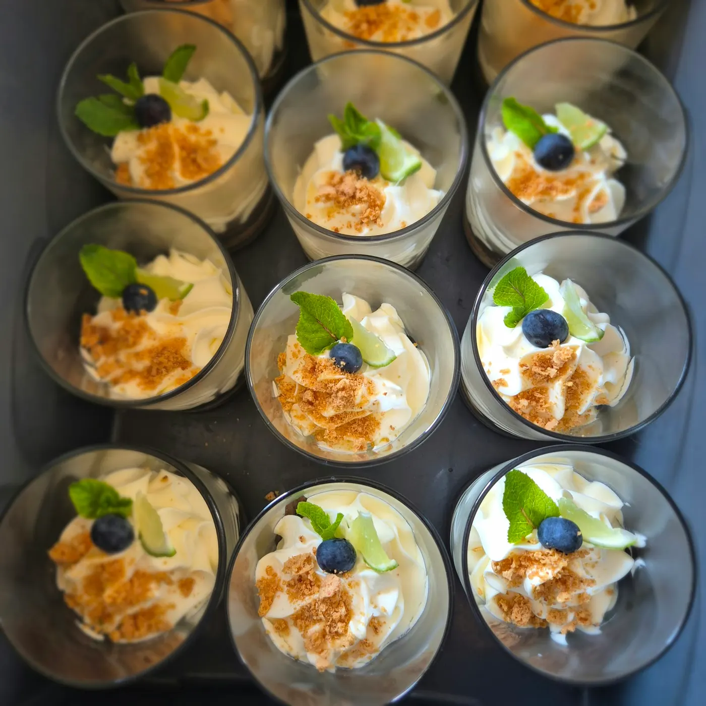 Dessert glasses with cream, biscuit crumbs and blueberries