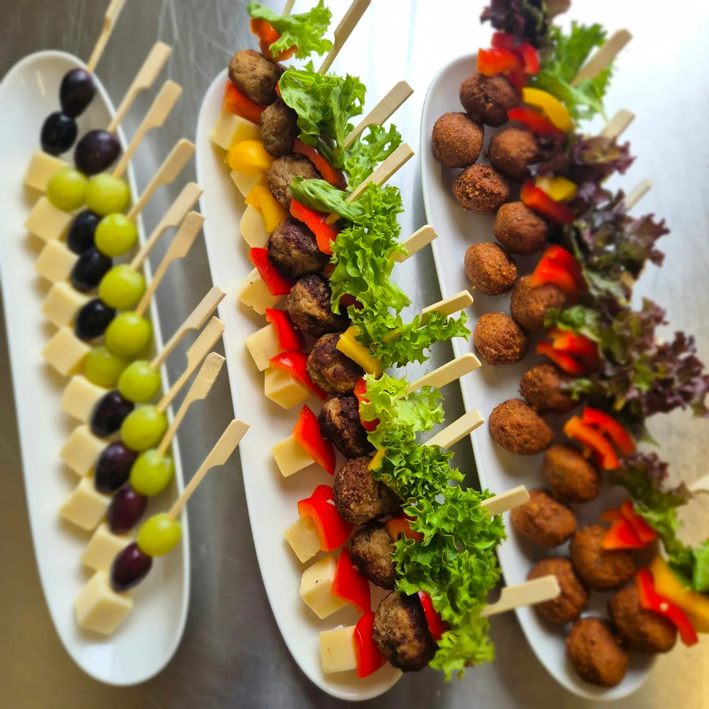 Cheese and grape skewers and meatball skewers on white platters