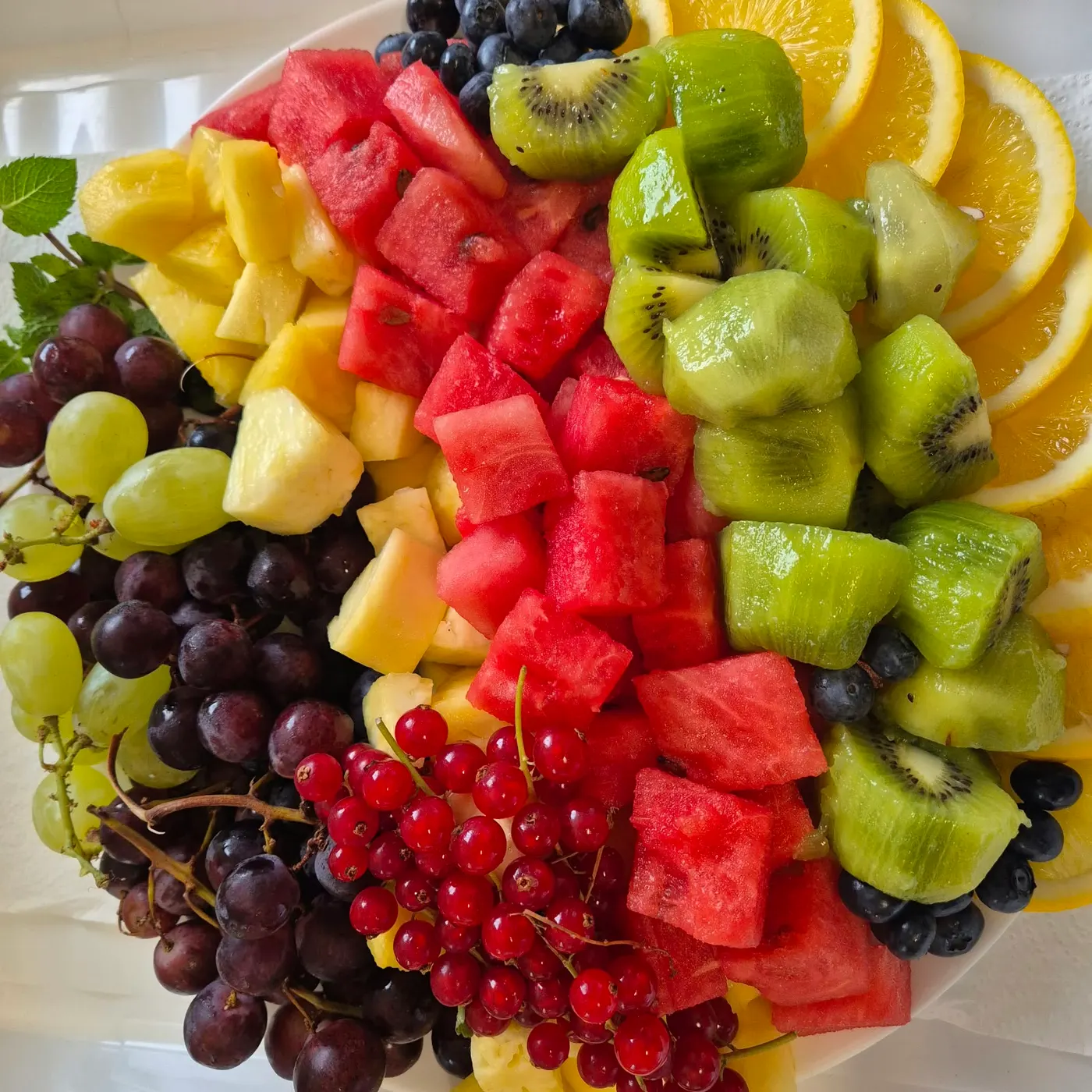 Fruit platter with melon, kiwi, pineapple, grapes and redcurrants