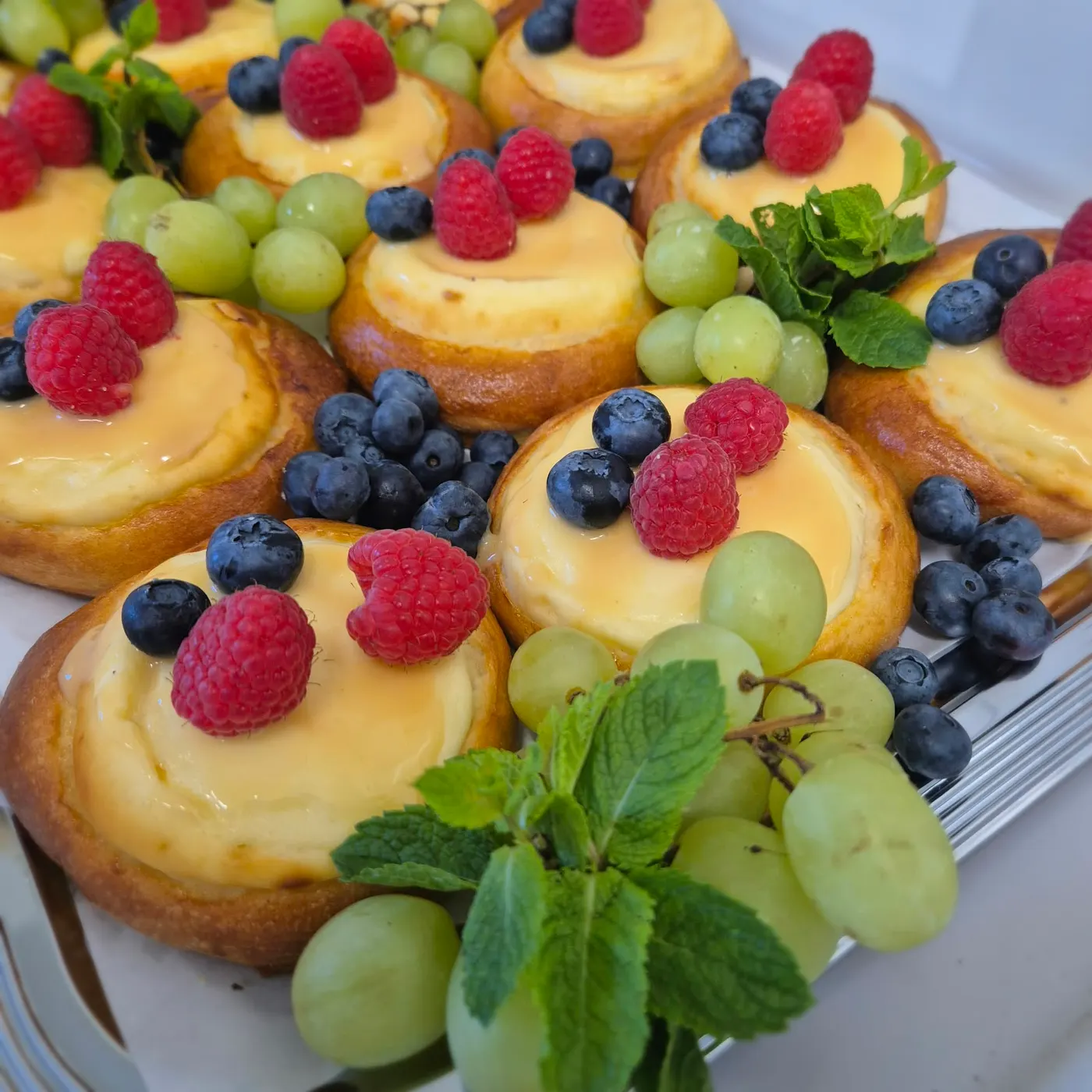 Custard pastries with raspberries, blueberries and grapes
