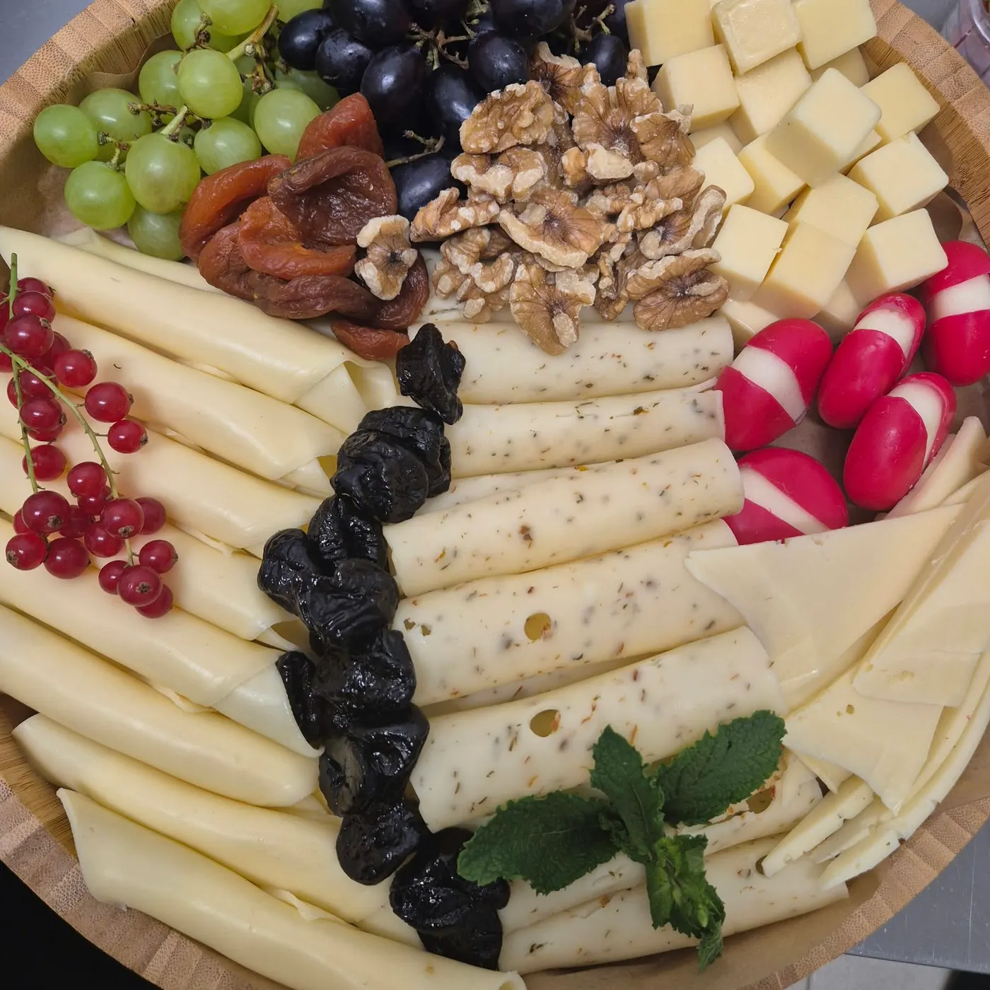 Cheese platter with walnuts, dried fruit and grapes