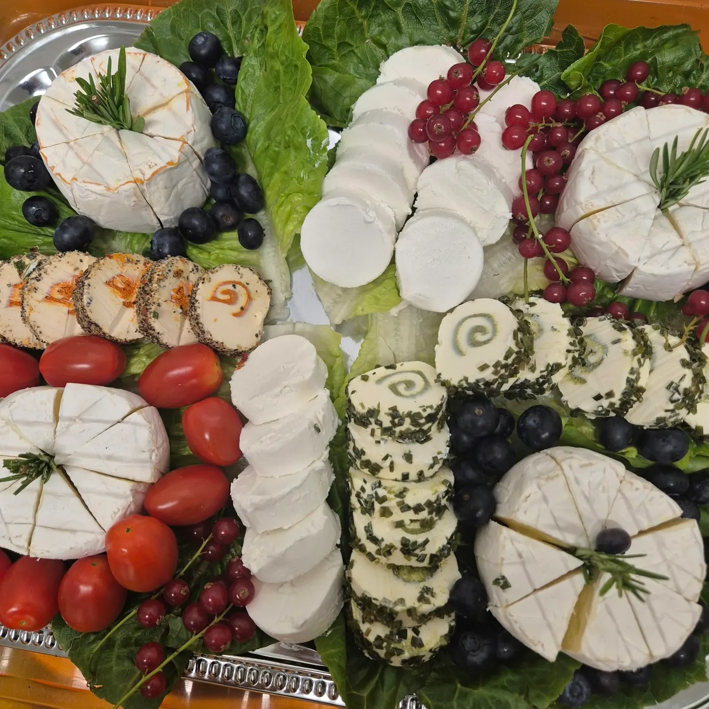 Cheese platter with camembert, cream cheese rolls and tomatoes