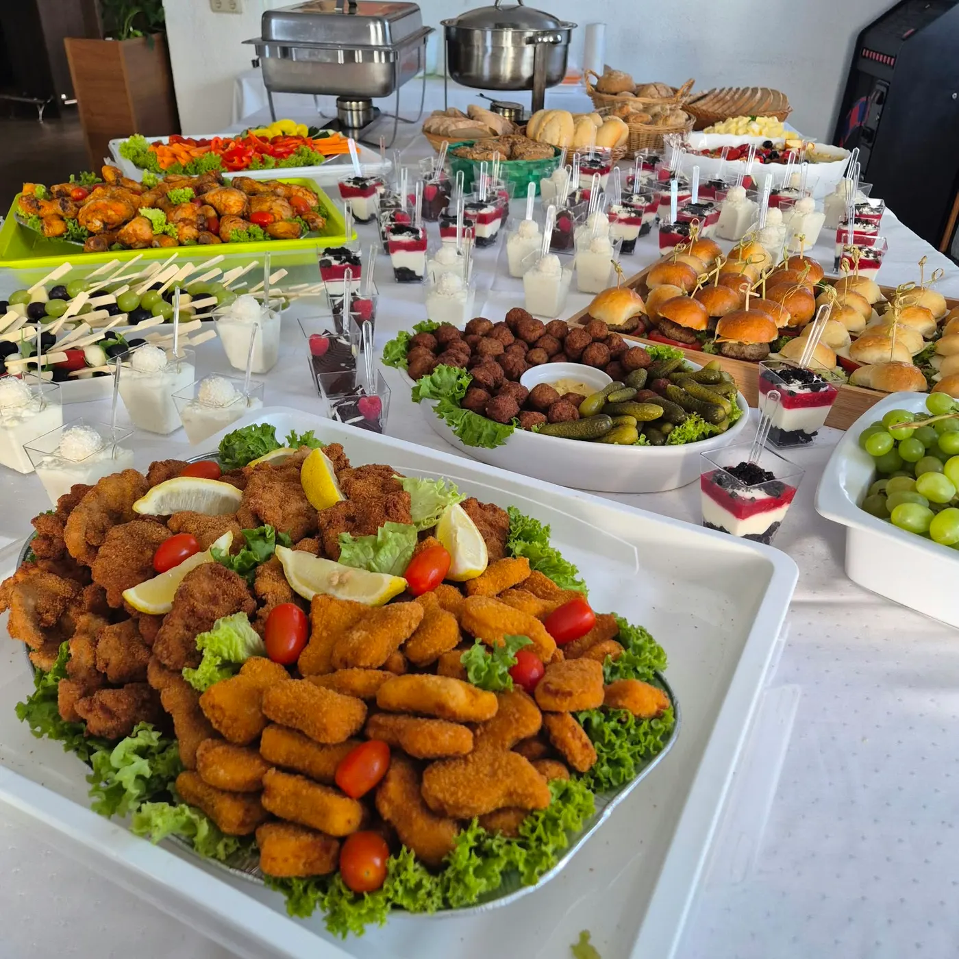 Buffet mit Hähnchen-Nuggets, Frikadellen, Mini-Burgern und Desserts im Glas
