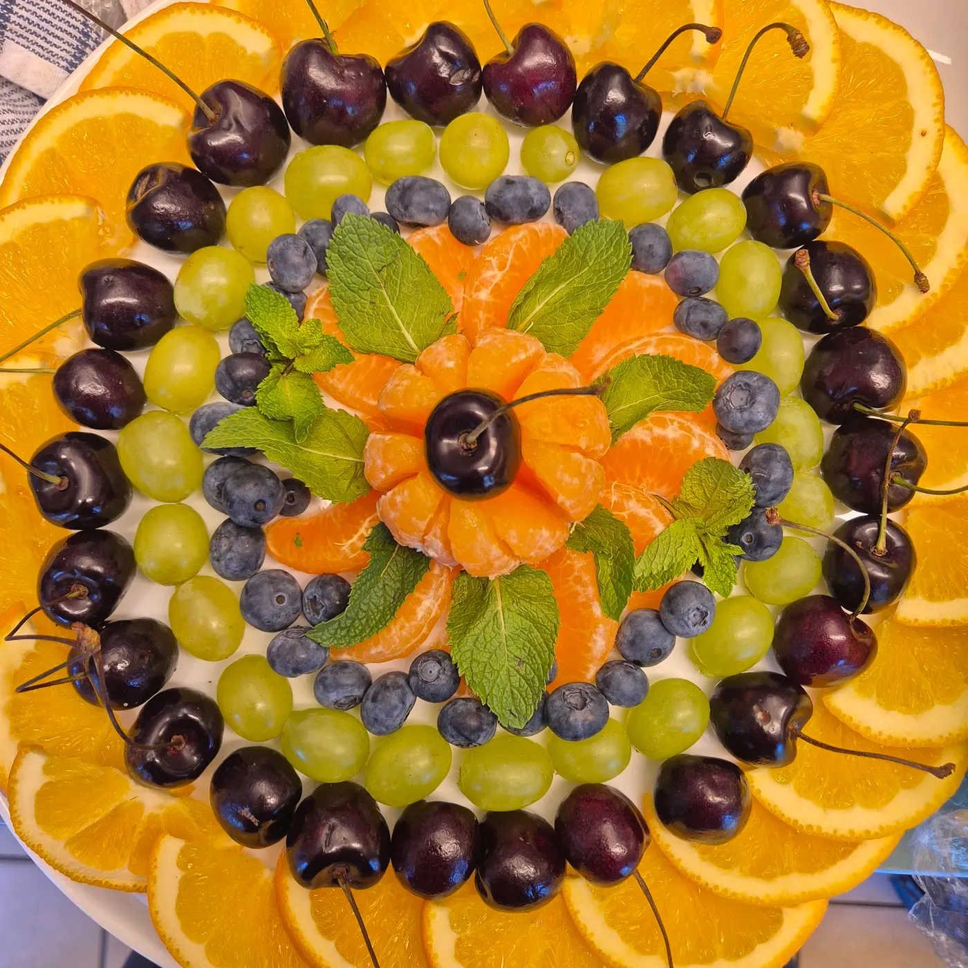 Fruit platter arranged in a circle with oranges, cherries, grapes and blueberries