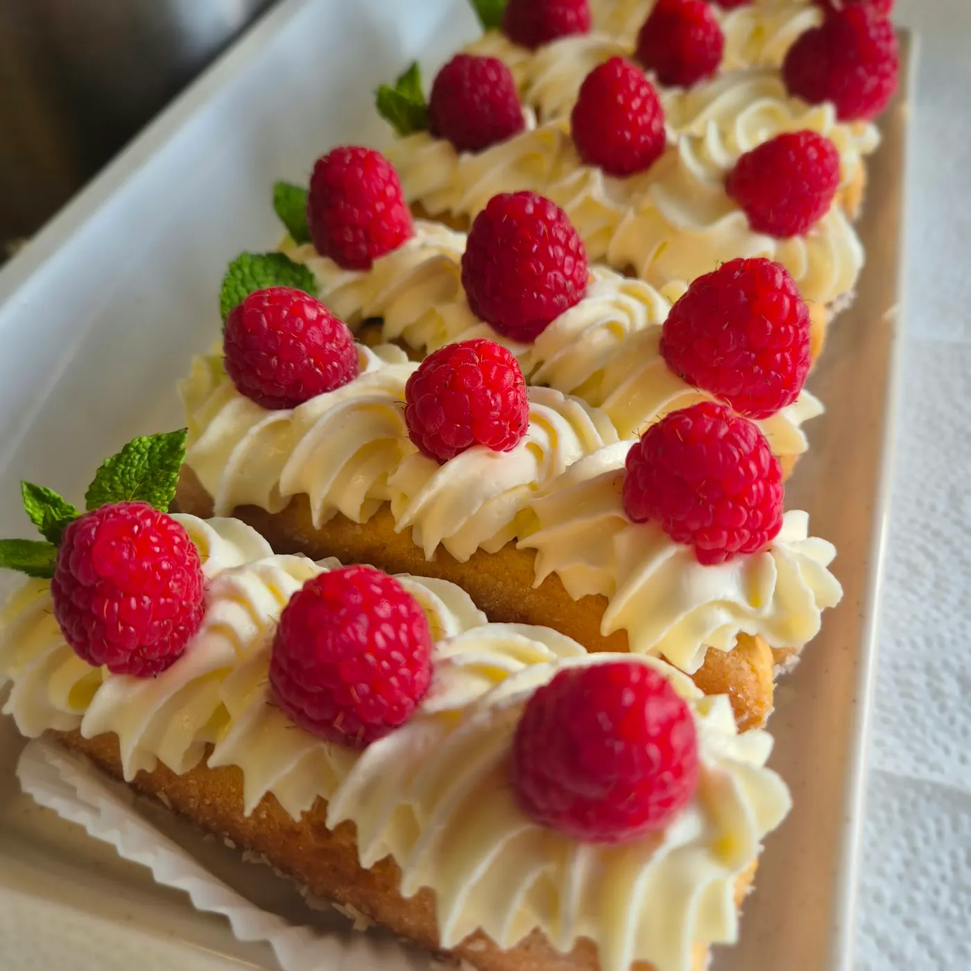 Cake slices with dollops of cream and raspberries