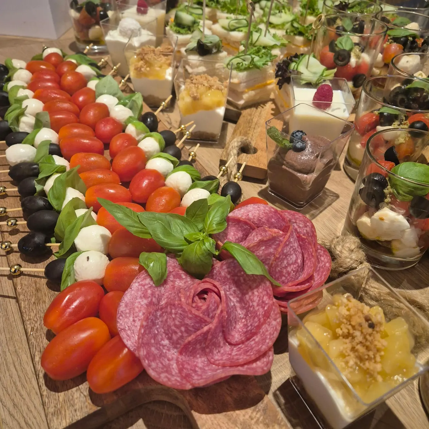 Tomato mozzarella skewers, a salami rose and desserts in glasses