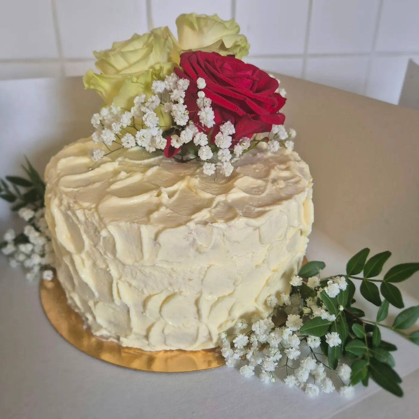 White cake with a red rose and baby's breath